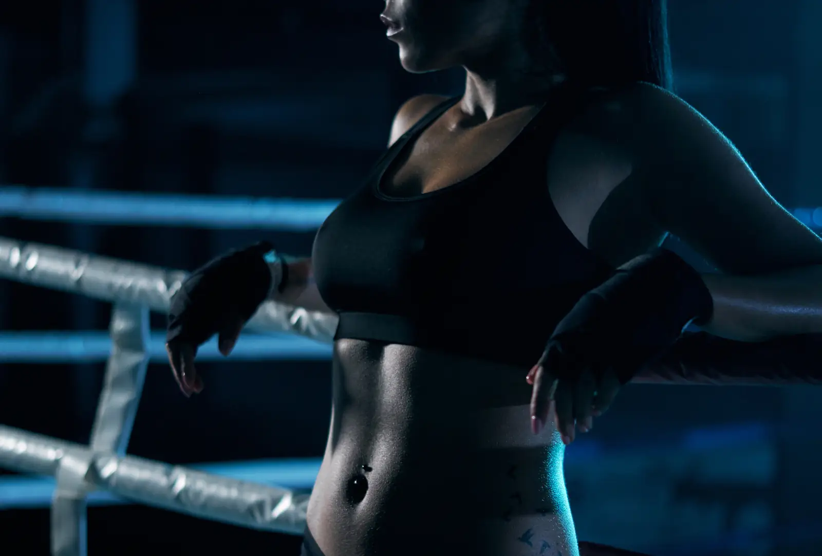 Female boxer resting on the ropes of a ring after training