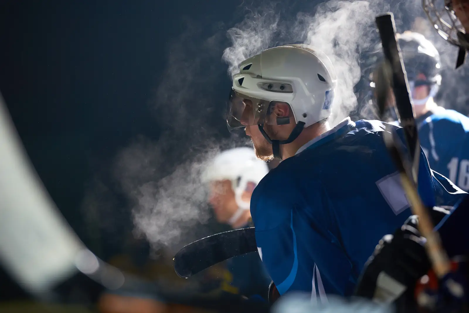 Ice hockey players on the bench, their breath visible in the cold rink