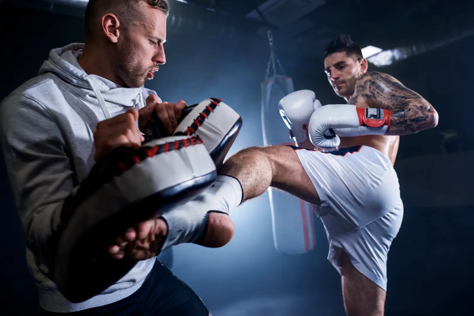 Kickboxing coach holding pads for an athlete in the gym