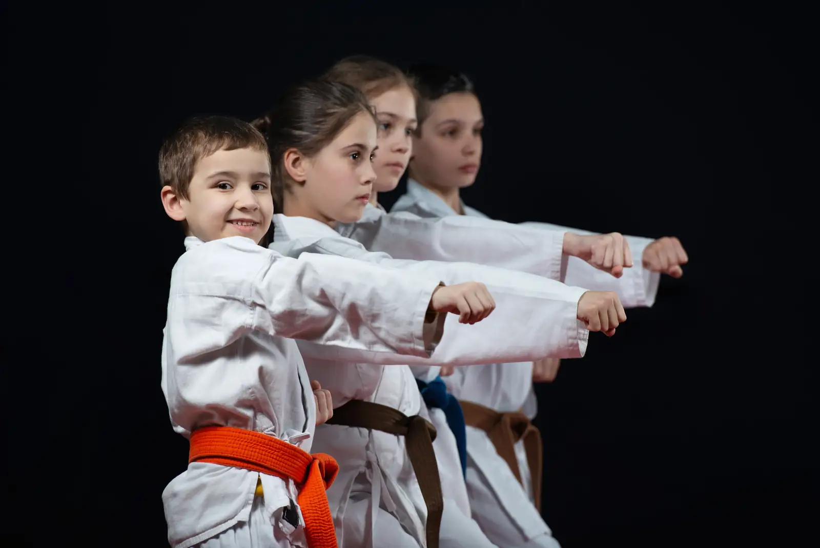 Children in karate uniforms practising punches in class