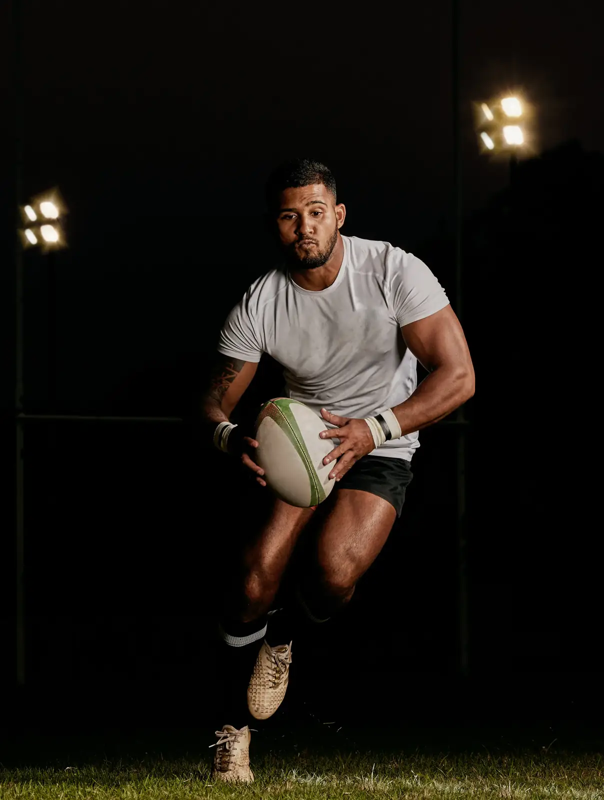 Rugby player running with the ball at night