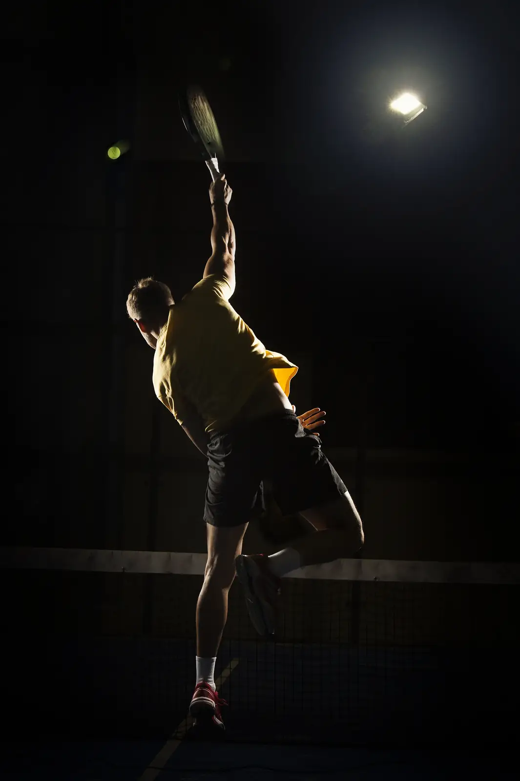 Tennis player serving on an indoor court