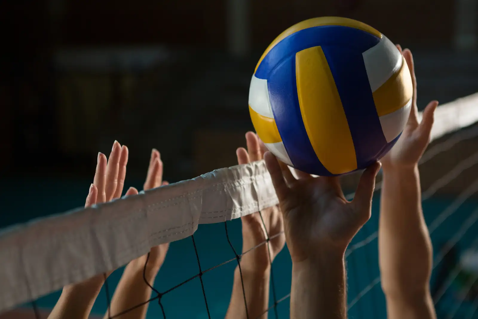 Volleyball players' hands reaching for the ball above the net