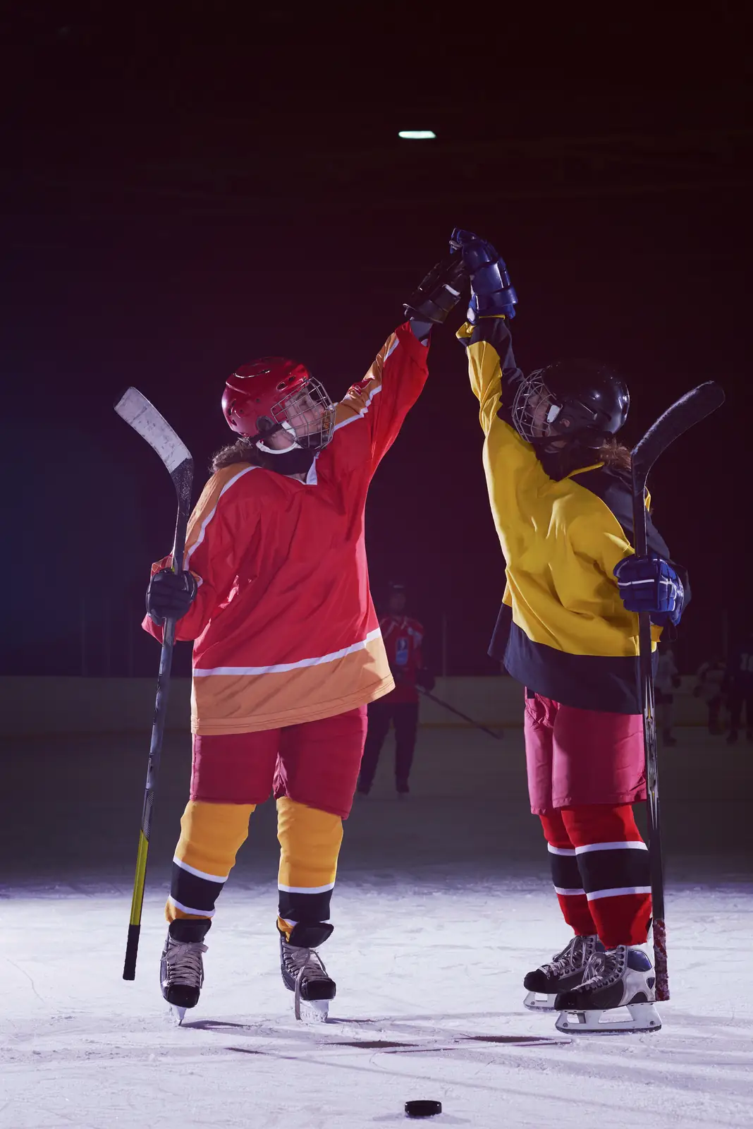 Two youth ice hockey players high-fiving after a goal